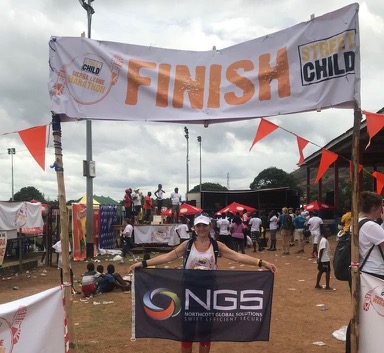 charity tracking runner at the finish line with NGS banner