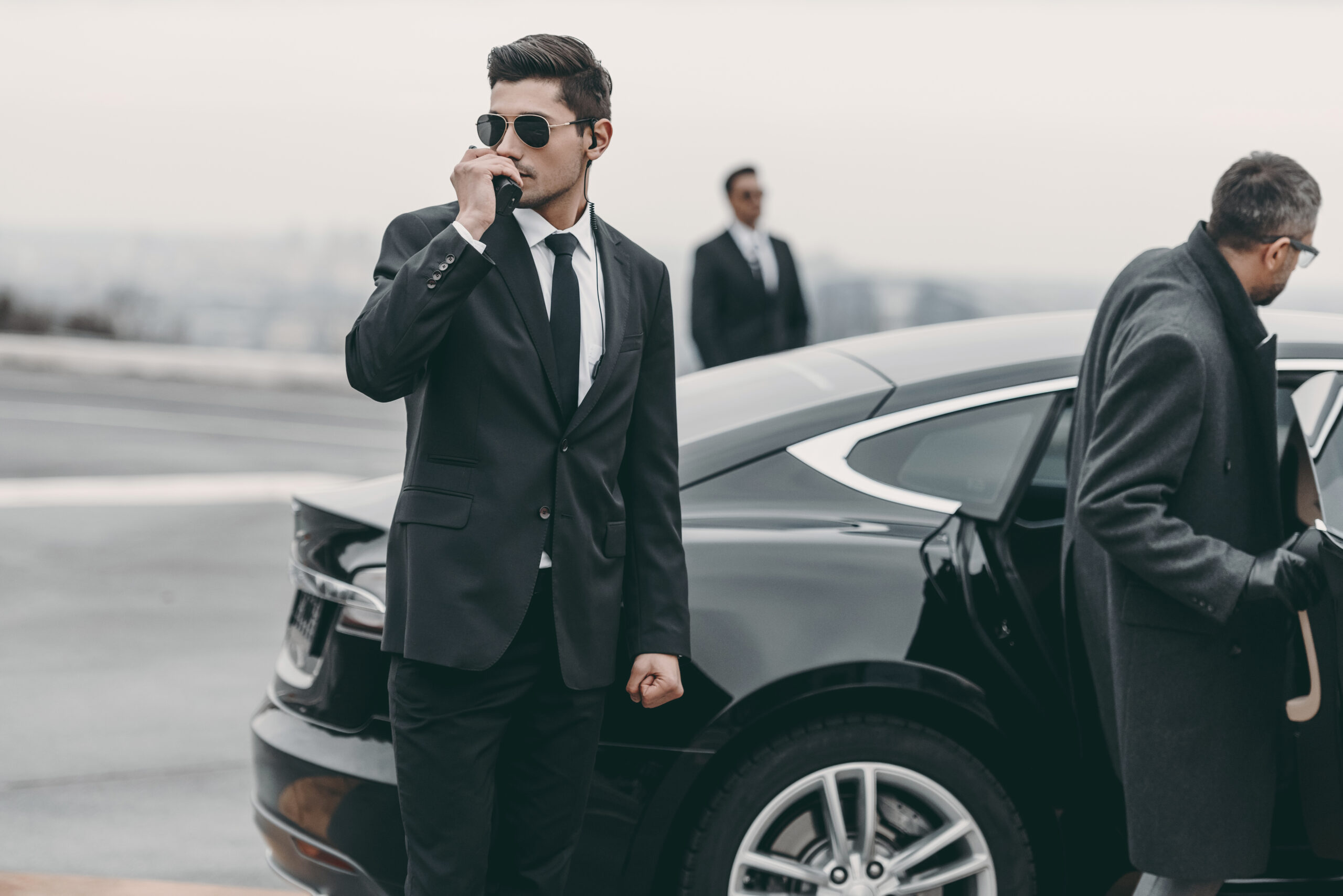Car driver updating corporate travel management company about the schedule as the passenger enters the car.