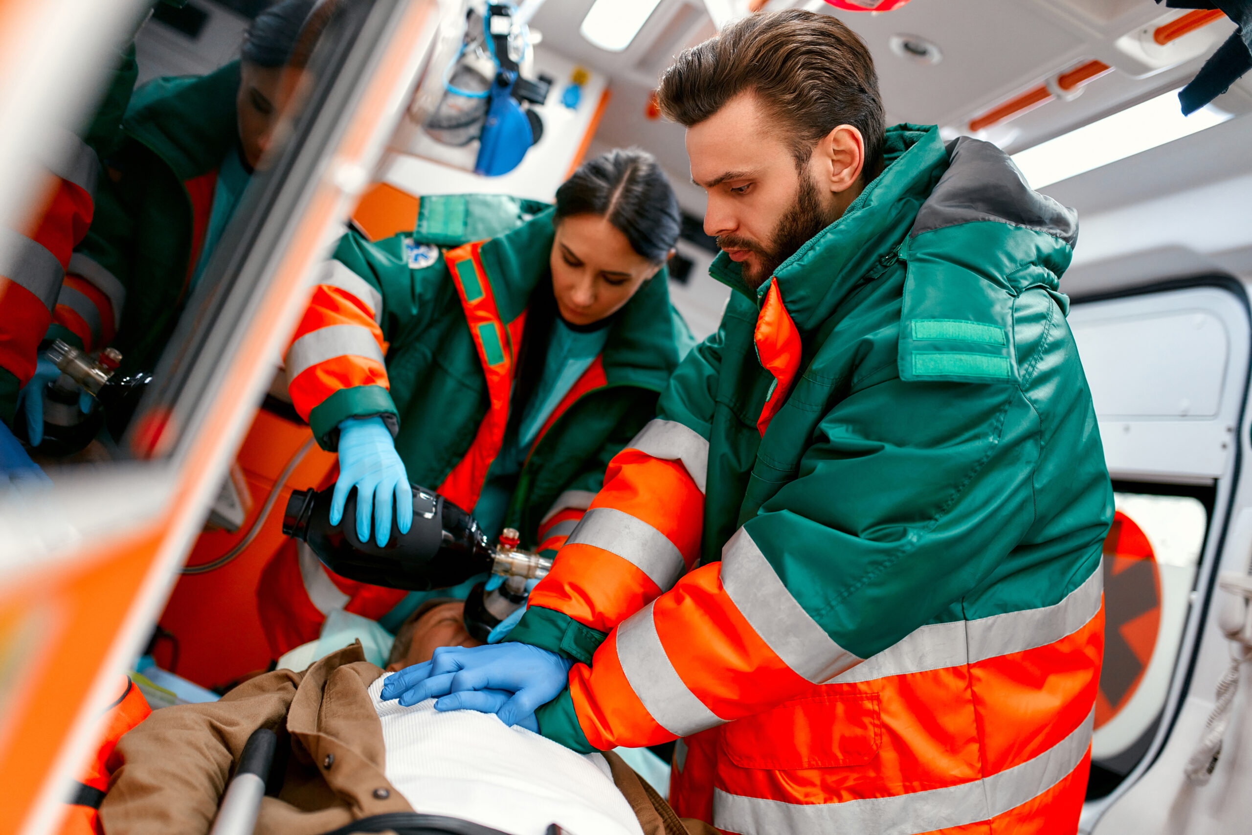 Two paramedics in an ambulance treating a patient during an emergency.